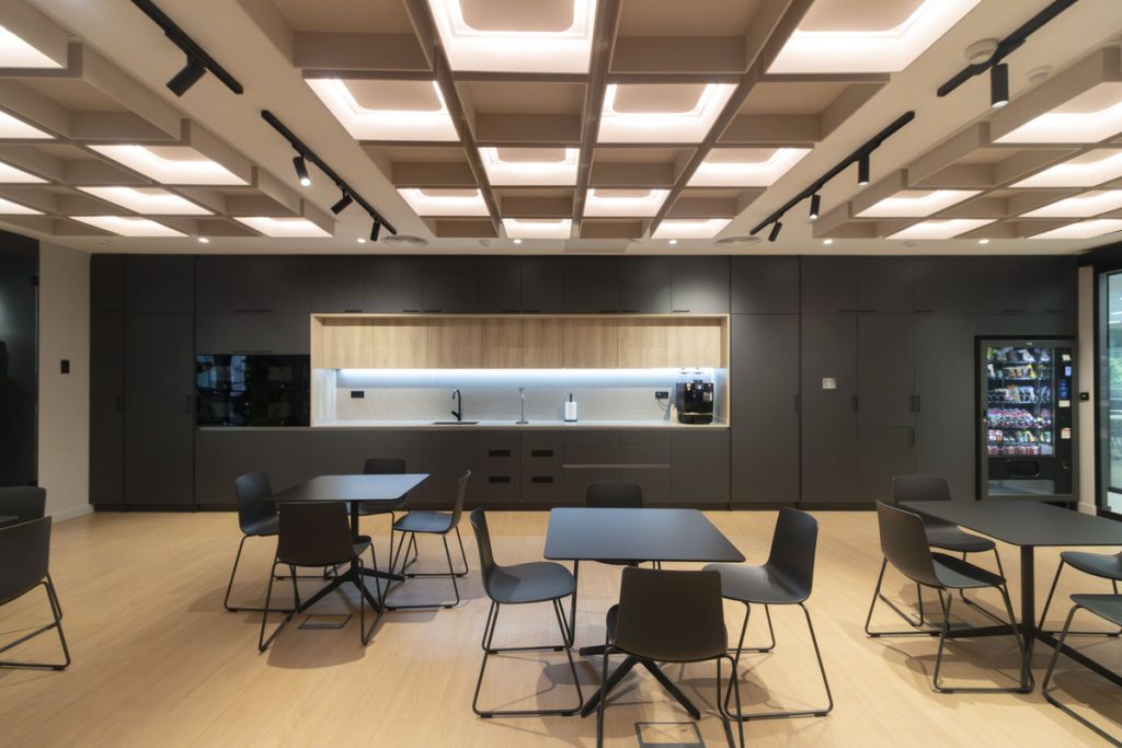 Espai social de les oficines de Wamos Air a Madrid amb mobiliari flexible i sostre acústic modular il·luminat.
